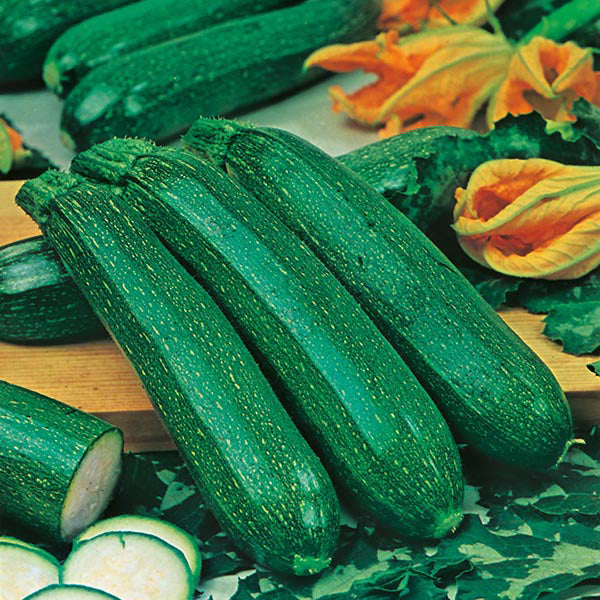 Green zucchinis on a wooden cutting board with flowers in the background